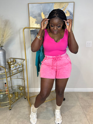 Side view of acid wash fleece shorts with drawstring and pockets
Full outfit with white sneakers and gold accessories in casual setting