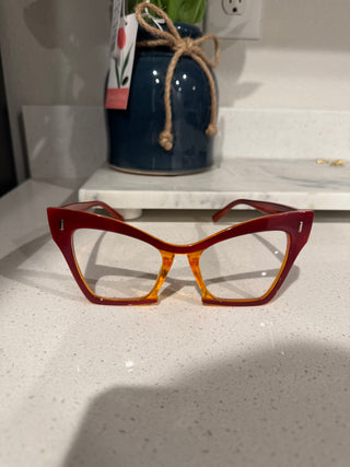 Bold colorblock red and amber glasses with oversized square frames, combining vibrant red and warm amber hues for a unique, fashion-forward look. Clear frames. Clear glasses. Clear sunglasses.